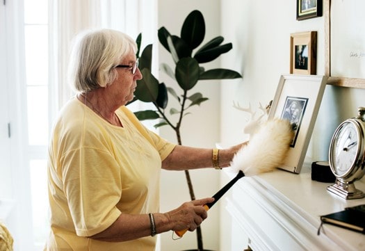 older lady dusting picture frame