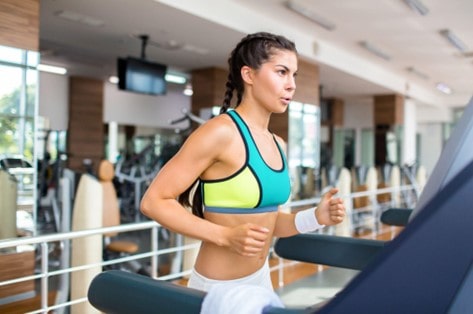 gym with girl running on treadmill breathing hard